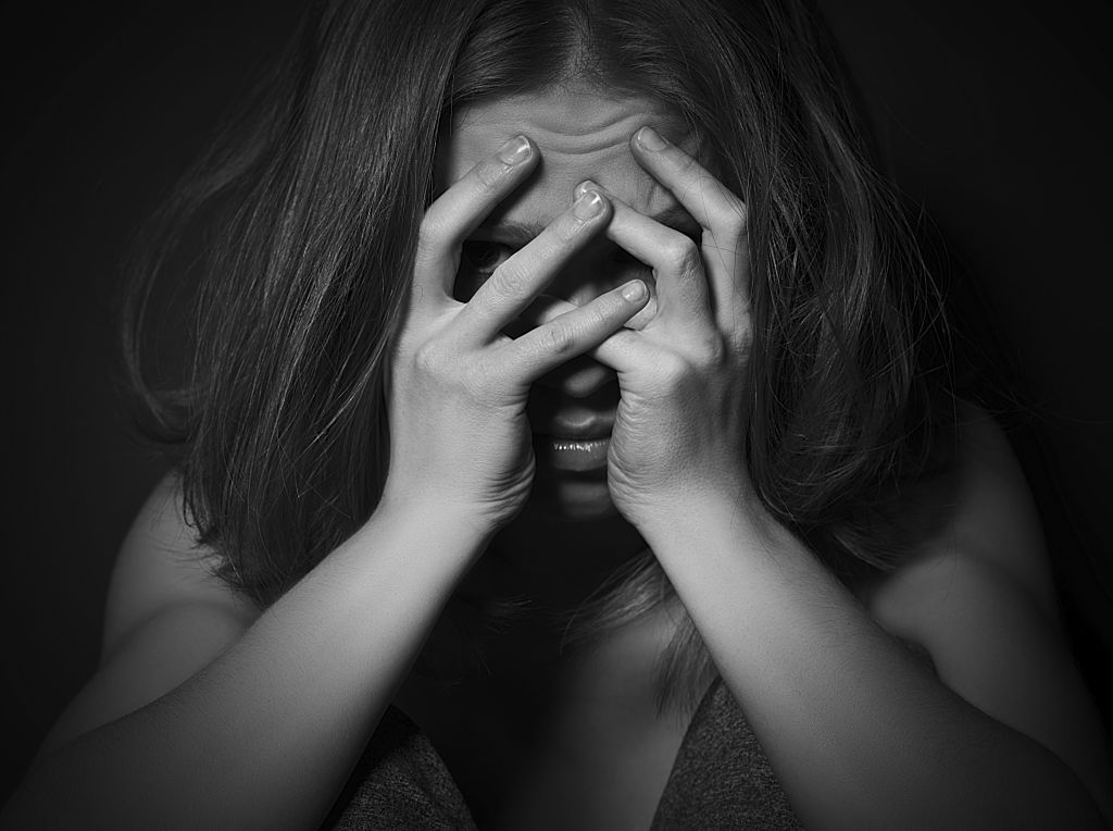 sad woman in depression and despair crying covered her face on black dark background