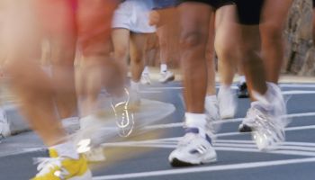 Blurred action image of runners feet during race, reflective shoes