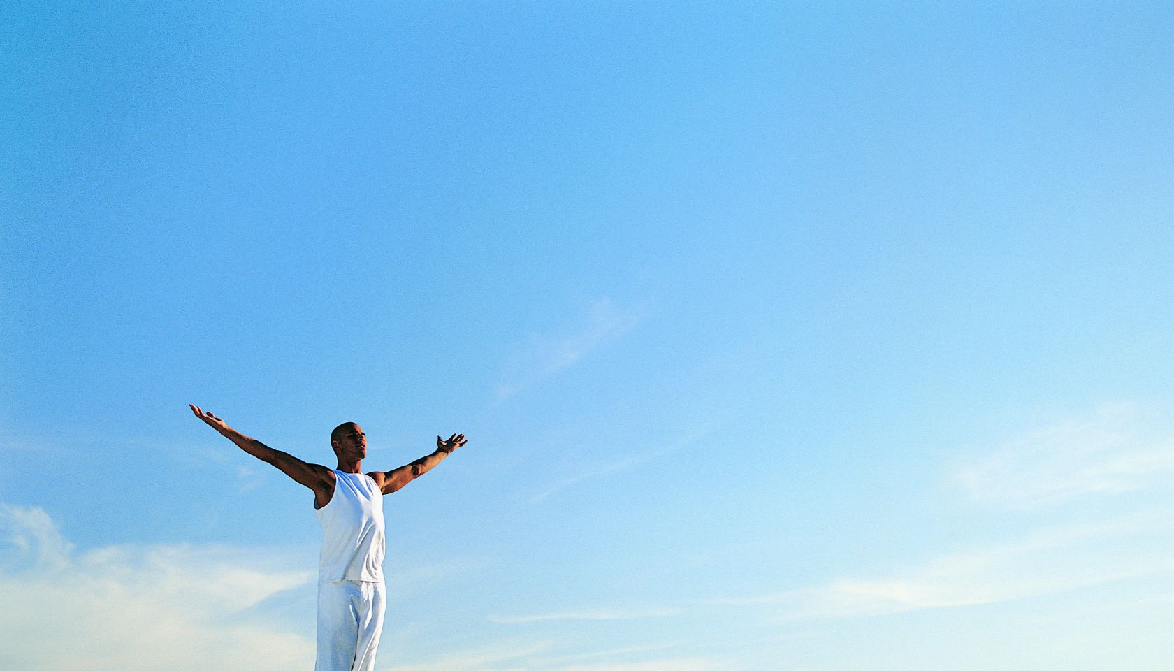 Man Standing on Boulder With Arms Outstretched