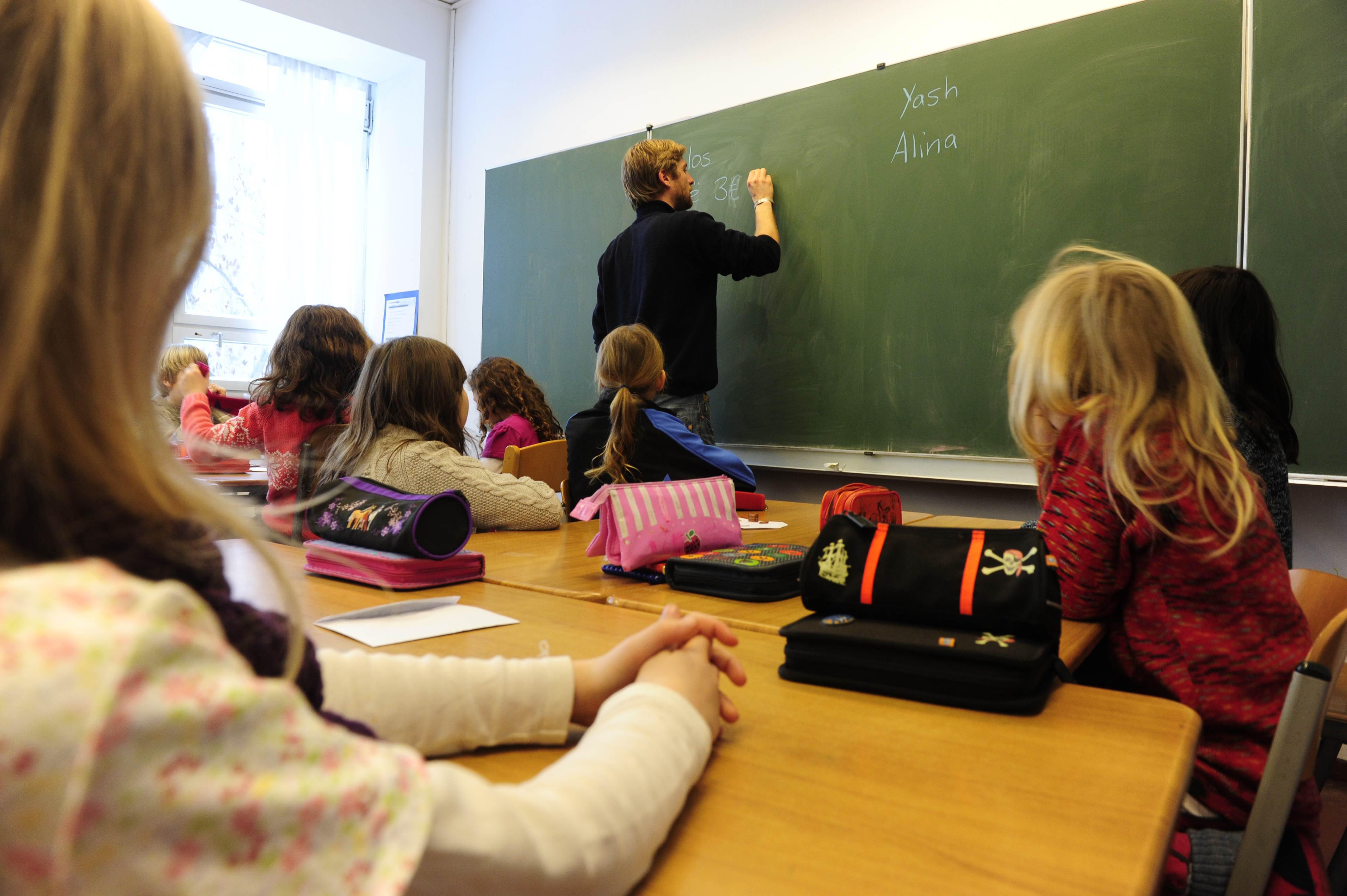 A teacher writes on the blackboard durin