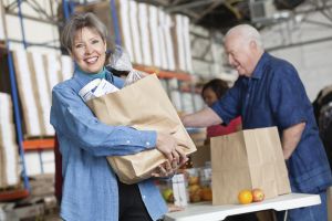 Happy mature woman holding groceries at food pantry