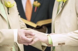 Man placing ring on another man's finger