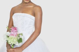 Midsection of bride holding bouquet over gray background