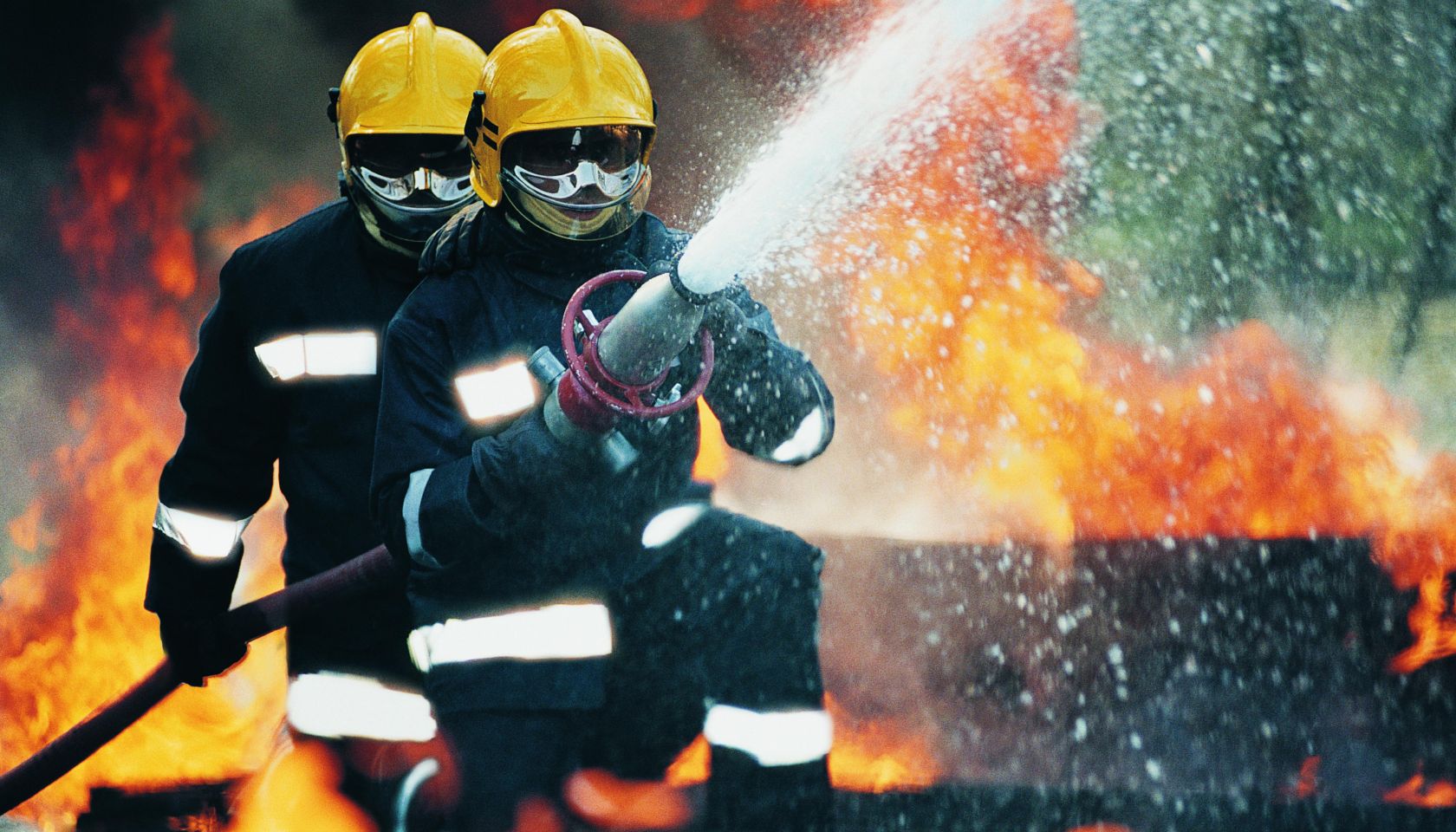 Firefighters Holding a Hose and Spraying Water
