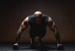 Man doing push-ups on dumbbells, studio shot