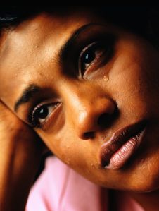 Woman crying, resting head against hand, close-up