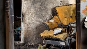 Burnt, Damaged Interior of Home with Destroyed Chair and Books