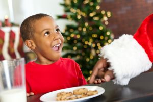 Surprised little boy sees Santa taking Christmas cookie