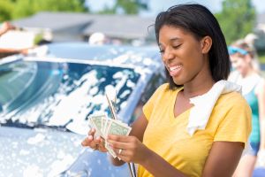 Confident African American teenage girl counts money at car wash