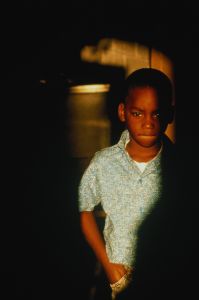 Boy (6-8) with sad look on face, surrounded by shadows