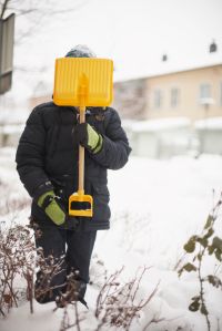 Child holding snow spade in front of face