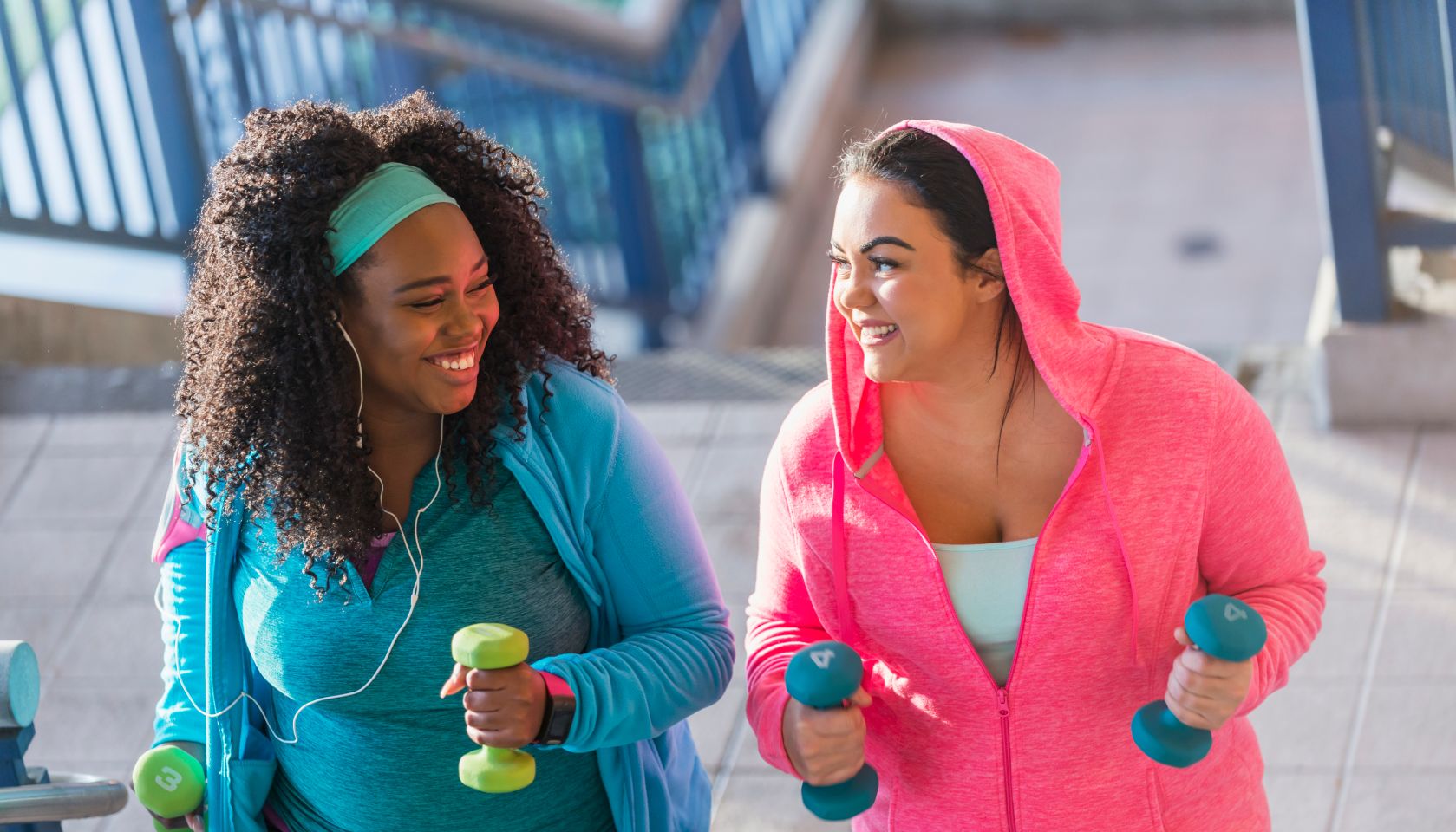 Two young women exercising, powerwalking up stairs