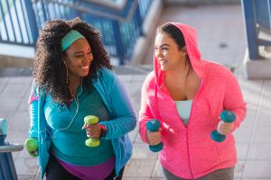 Two young women exercising, powerwalking up stairs