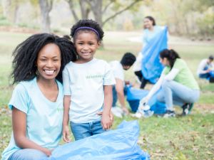 Mother volunteers with young daughter for community cleanup