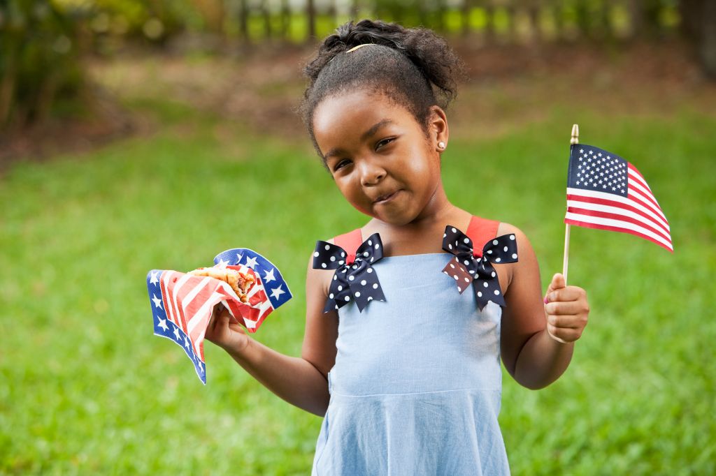Little girl with American flag and hotdog