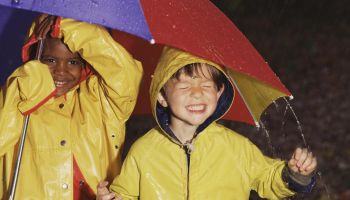 Boys playing in rain under umbrella