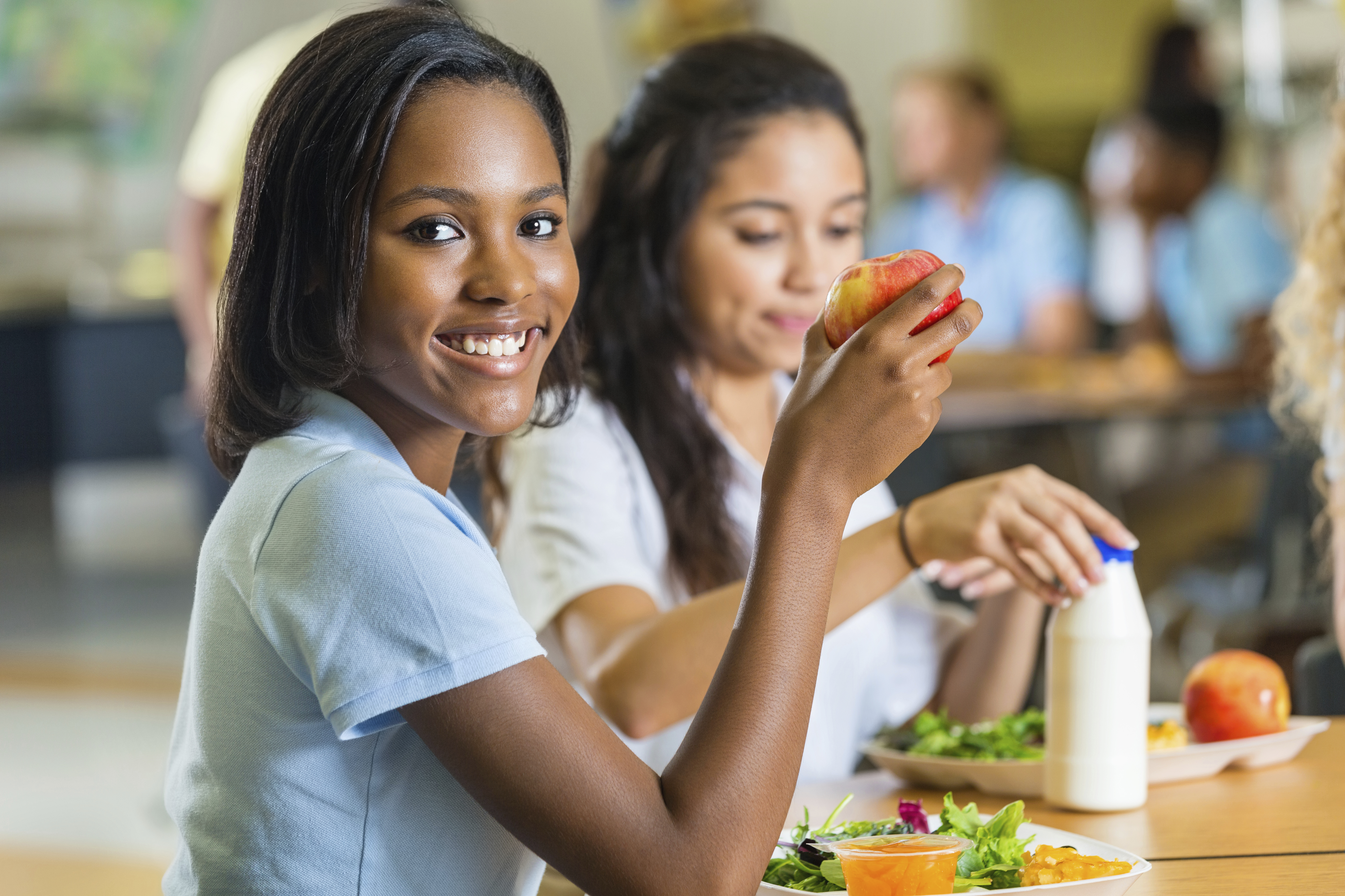 Teenager eating healthy lunch with friends in school lunchroom
