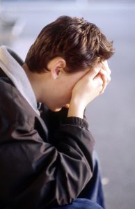 depressed teenager sitting with head in hands