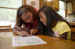 African American teen looks at map with mom