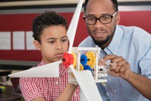 Teacher helping student with model wind turbine