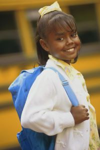 Girl with backpack by school bus