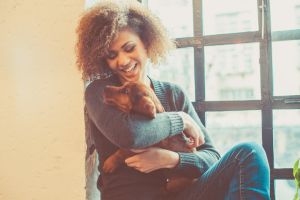 attractive young african woman playing with puppy