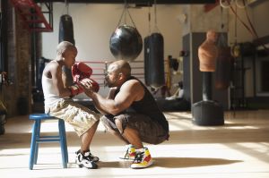 Father talking to son wearing boxing gloves