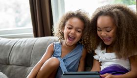Mixed race girls using digital tablet on sofa