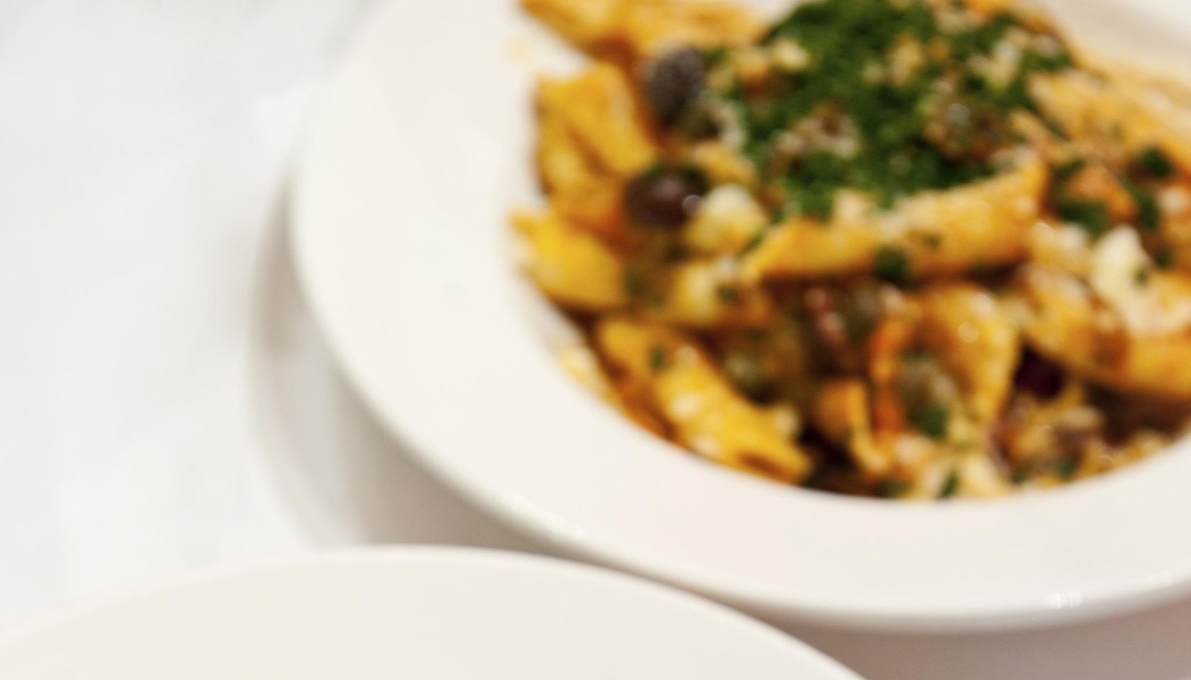 Penne Matriciana Italian Pasta on a plate in restaurant with Parmesan Cheese and Parsley.