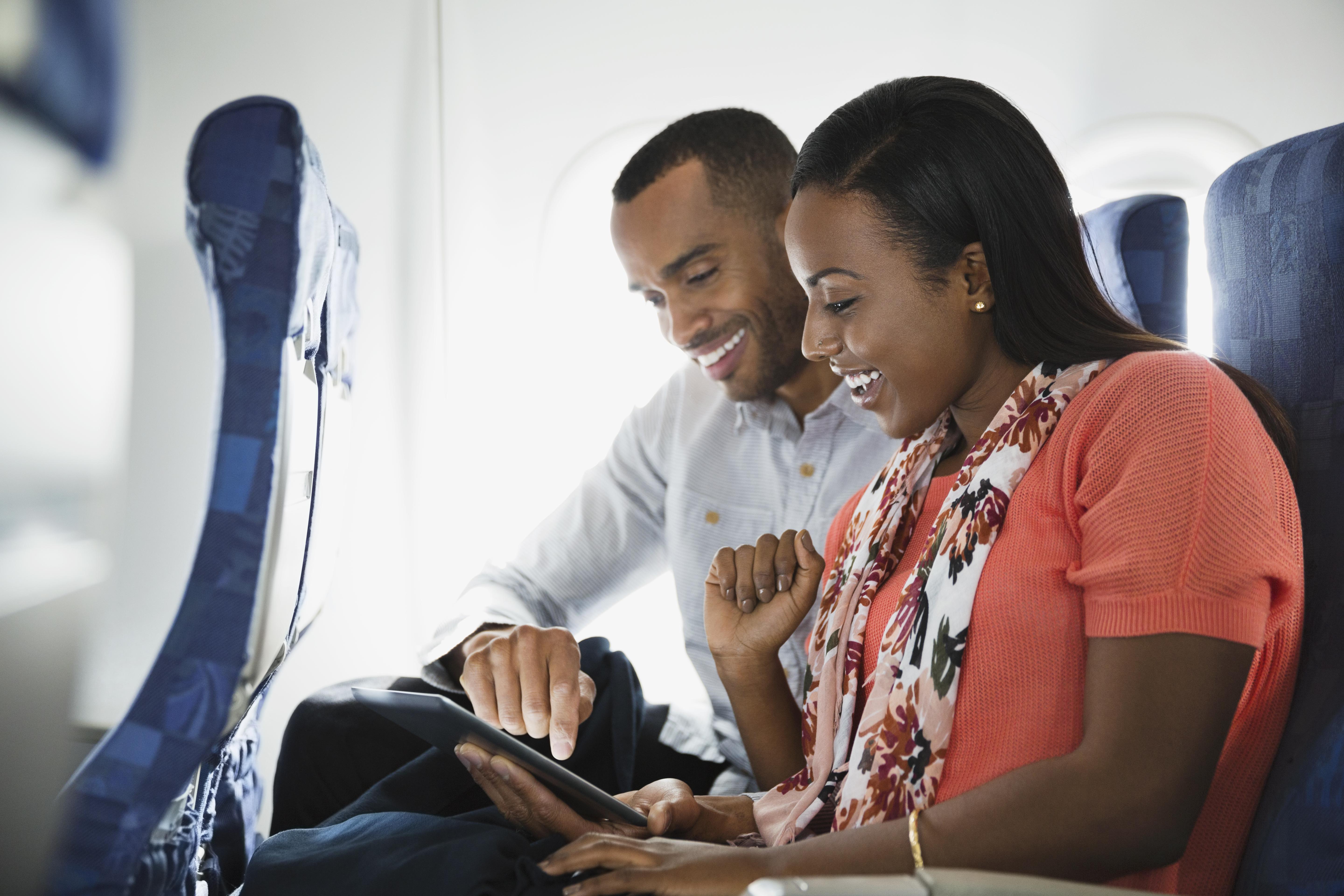 Couple using digital tablet in airplane