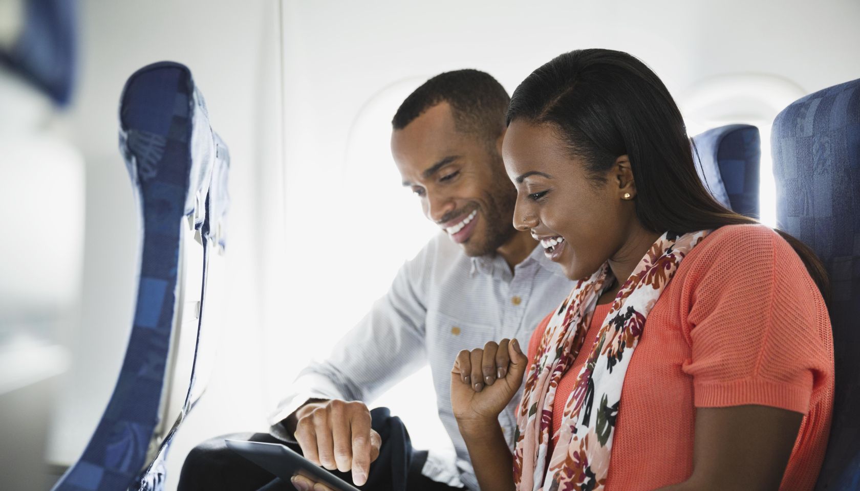 Couple using digital tablet in airplane