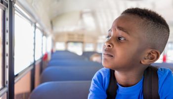 Young boy worriedly looks out bus window