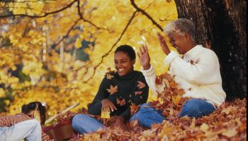 Three generation family playing with autumn leaves