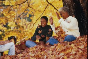 Three generation family playing with autumn leaves