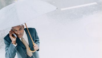 Young man with umbrella using mobile phone, elevated view