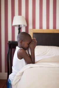 African boy saying prayers at bedside