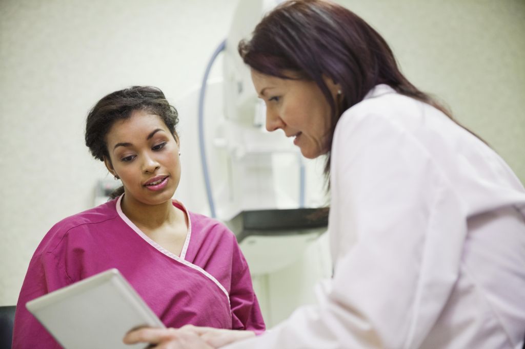 Mature doctor using digital tablet to explain to female patient