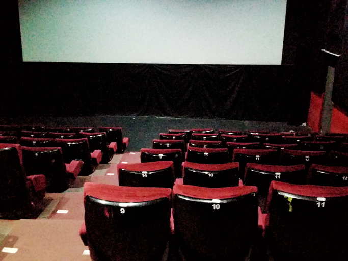 Empty Movie Theater Auditorium With Red Seats And Blank Screen