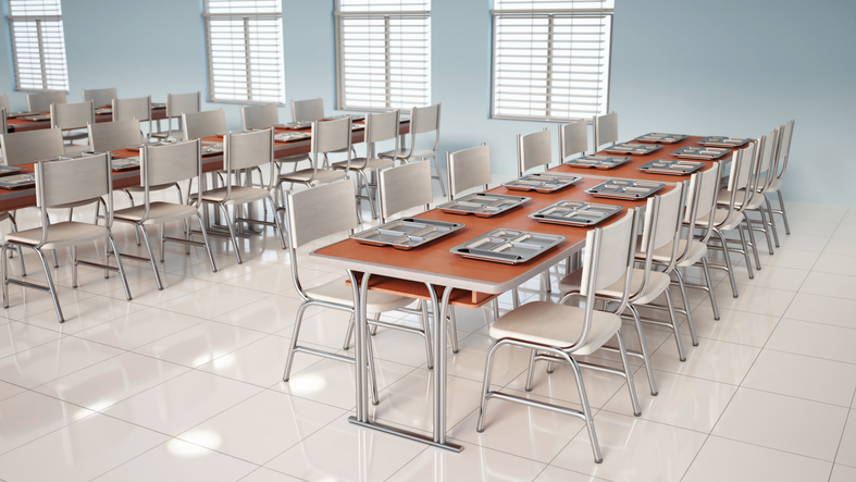Rows of empty tables in a bright cafeteria with windows during daytime